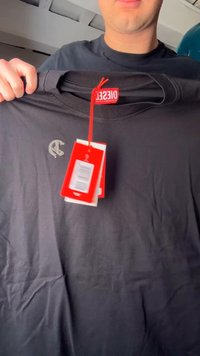 Άτομο κρατάει μαύρο t-shirt Diesel με κόκκινες ετικέτες και μικρό κεντητό λογότυπο κοντά στην αριστερή περιοχή του στήθους.