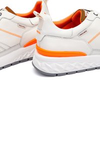 Zapatillas de cuero blancas con acentos naranjas, suela de goma gris texturizada y costuras de contraste. Incluye una pestaña de tira y un logo de marca.