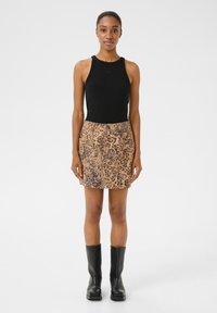 Top negru fără mâneci, asortat cu o fustă mini bej, cu un model de leopard. Modelul poartă cizme negre până la genunchi.