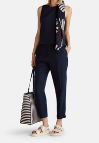 Navy sleeveless top, matching trousers, and cream sandals. Includes a floral-patterned scarf and a striped tote bag with shoulder straps.