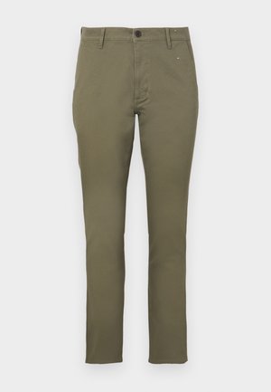 Chino slim-fit verde oliva in cotone con texture liscia. Presenta una chiusura con bottone e quattro tasche. Design semplice e minimalista.