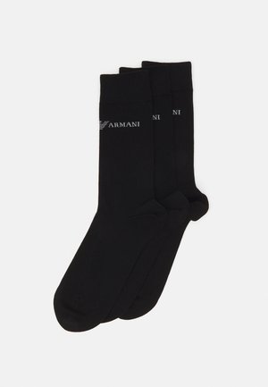 Tre paia di calzini neri realizzati in un materiale morbido ed elastico, con un design semplice e il logo "Armani" in grigio vicino alla parte superiore.