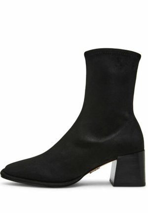 Stivale alla caviglia nero in materiale liscio con punta affusolata e tacco quadrato chunky. Design senza cuciture con parte superiore elasticizzata per una facile calzata.