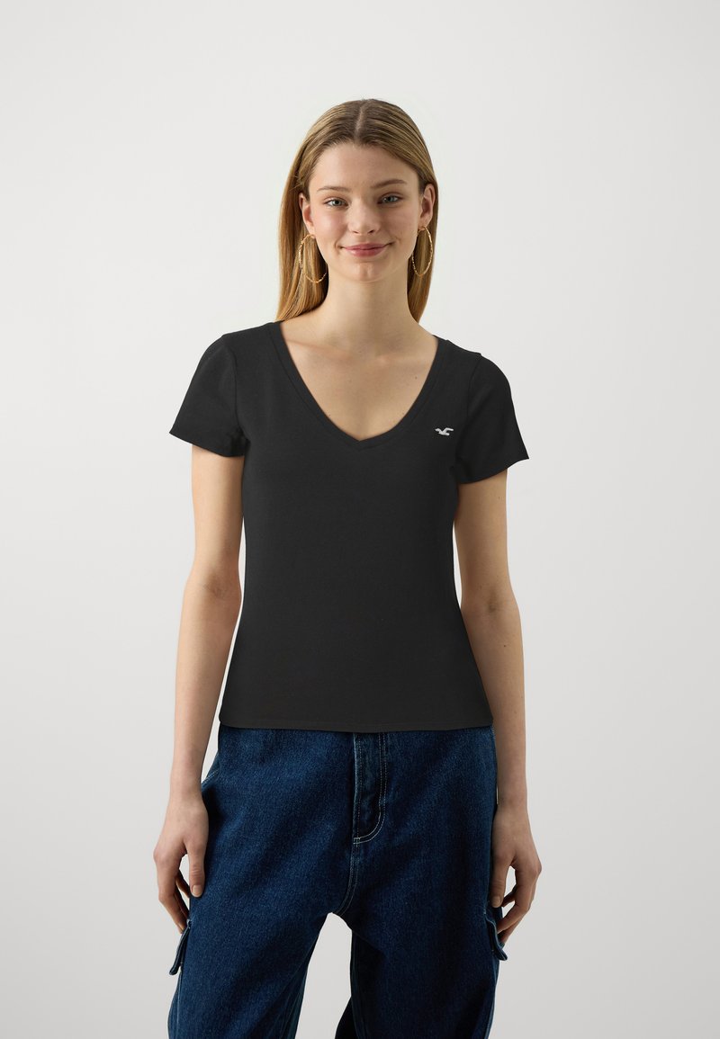 Czarny bawełniany T-shirt z dekoltem w serek i krótkimi rękawami, z małym białym logo na lewej piersi oraz dopasowanym krojem.