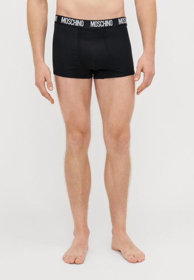 Čierne bavlnené boxerky s bielym pásom s logom Moschino, ktoré majú priliehavý strih a hladkú textúru.