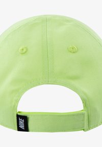 Neon zöld sapka ívelt karimával, texturált anyagból; hátul található egy pánt fekete Nike címkével, valamint hímzett szellőzőnyílások.