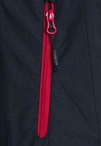 Tissu noir avec une fermeture éclair rouge proéminente, équipée d'un curseur noir et du logo CMP. Texture lisse avec une couture durable.