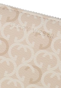 Portafoglio beige con logo Gerry Weber in rilievo e motivo circolare ripetuto. Materiale sintetico liscio con finitura testurizzata e chiusura con zip.