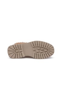 Der mit Gummi besohlte Stiefel verfügt über eine strukturierte, beige Außensohle mit tiefen Rillen für besseren Halt, ergänzt durch ein weiches, pelziges Obermaterial in Pfirsich.