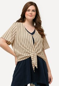 Beige og sort stribet bluse med korte ærmer, V-hals og knude-detail foran. Har fem knapper ved halsudskæringen. Blødt materiale.