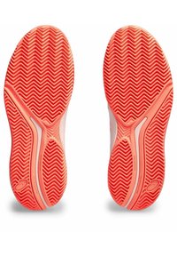 Zapatillas deportivas con una suela de goma texturizada de color naranja con un patrón en espiga y una parte superior suave de color claro.