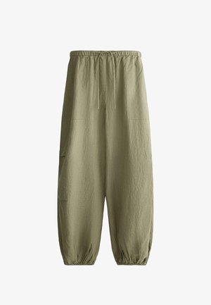 Løse olivengrønne bukser med elastisk taljebånd, snøre, store for- og sidelommer samt elastiske manchetter ved anklerne.