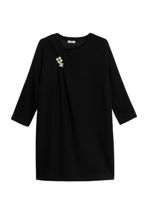 Sort kjole med trekvartlange ærmer, med et draperet design og en blomsterbroche som accent på venstre skulder. Glat stoftekstur.