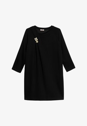 Czarna sukienka z rękawami do połowy ramienia, z drapowanym wzorem i kwiatową broszką na lewym ramieniu. Gładka faktura tkaniny.