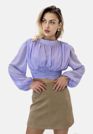 Lavendelgekleurde cropped blouse met pofmouwen en plooidetails, gecombineerd met een beige suède minirok. Gladde textuur en een aansluitende pasvorm.