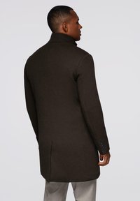 Abrigo de lana marrón con un cuello alto, diseño entallado y textura suave. Presenta dos aberturas traseras y puños abotonados.