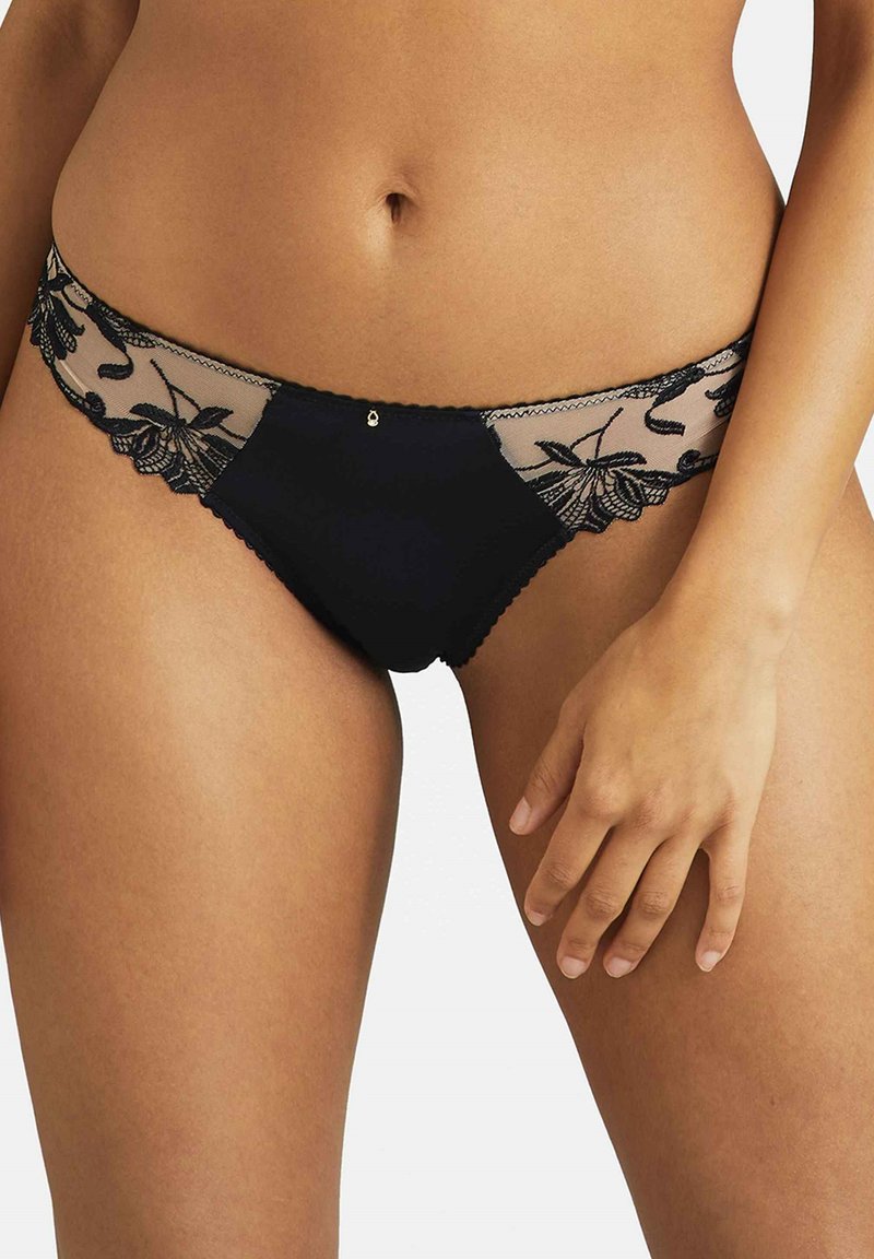 Sous-vêtements noirs avec des panneaux de dentelle florale, un devant noir uni et des bords festonnés. Présente un détail accentué au centre devant.