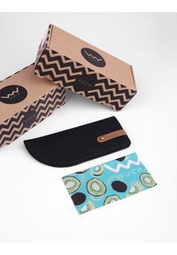 Černá plstěná pouzdro na tužky s zakřiveným vrchem, hnědým koženým akcentem a logem. Dvě kartonové krabice s vzorem v podobě cik-cak v pozadí.