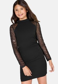 Schwarzes Kleid mit taillierter Passform und durchsichtigen langen Ärmeln, die mit Pailletten verziert sind. Hoher Kragen und glattes Material über das gesamte Kleid.