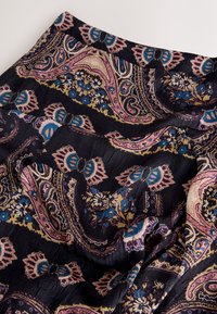 Tissu noir avec un motif cachemire en rose, bleu et or. Présente des accents floraux et une texture froissée. Design doux et léger.