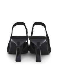 Escarpins noirs à talon slingback avec une finition brillante, dotés d'un talon élancé et d'une texture en daim doux. Design à dos ouvert avec une silhouette minimaliste.