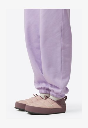 Gewatteerde instapschoenen in lichtroze met een bruine zool. Gecombineerd met lavendelkleurige joggingbroeken met elastische boorden. Zacht, gevoerd ontwerp.