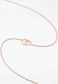 Halsband i roséguld med två sammanflätade hjärtan som central detalj, med en delikat kedjedesign. Slät yta och polerad finish.