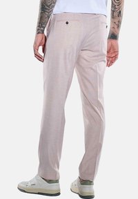 Beige Hosen aus leichtem Stoff mit subtiler Textur, zwei Gesäßtaschen mit schwarzen Knöpfen und geradem Schnitt.