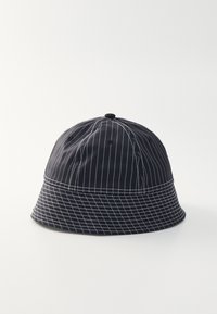 Svart bucket hat med vita randiga mönster, tillverkad av tyg med en slät yta, med en rund krona och en bred platt skärm.