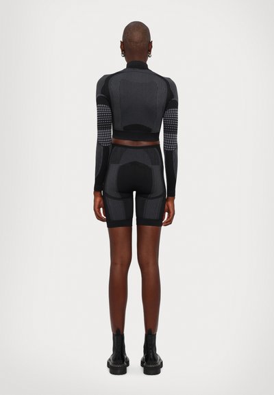 Black athletic set featuring a long-sleeve top and high-waisted shorts. Textured patterns and snug fit. Includes ankle-length black boots.