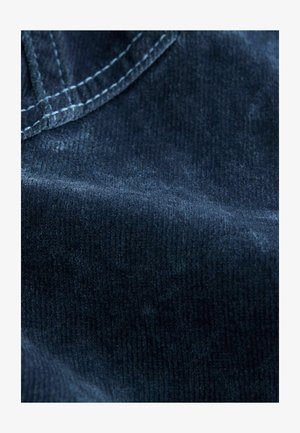 Tumedat sinelise värvi korduroo kangas pehme tekstuuriga, millel on peened, vertikaalsed ribad. Nähtav õmblus servade mööda lisab pinnale detaili.