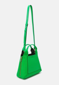 Zelená kožená kabelka se strukturovaným tvarem, s dvojitými rukojeťmi, odnímatelným popruhem a zipovým uzávěrem na jedné straně.