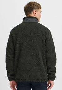 Dark green fleece jacket with a soft, textured surface. It features a high collar and long sleeves, designed for warmth and comfort.