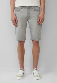 Shorts en denim gris clair à coupe droite, avec cinq poches et un ourlet retourné, associés à des baskets blanches et grises.
