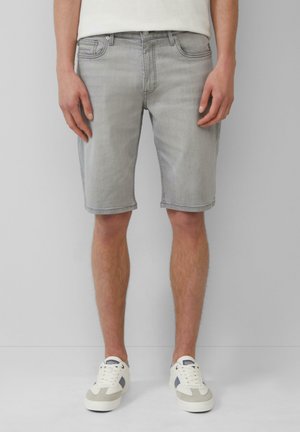 Shorts en denim gris clair à coupe droite, avec cinq poches et un ourlet retourné, associés à des baskets blanches et grises.