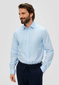 Chemise à manches longues bleu clair avec un devant à boutons et un col pointu, fabriquée dans un tissu lisse ; associée à un pantalon marine doté d'une taille élastique.