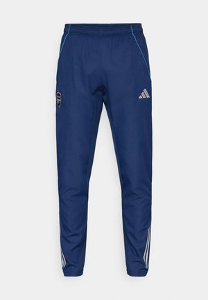Pantalons de jogging bleu marine en tissu léger, avec un accent bleu, un patch logo et trois rayures blanches le long des jambes.