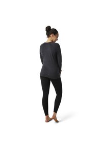 Grijze langharige top met een losse pasvorm, gecombineerd met zwarte legging. Het materiaal ziet er glad en rekbaar uit, ideaal voor actieve kleding.