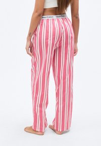 Ροζ και λευκή ριγέ πυτζάμα με ελαστική μέση που φέρει το όνομα της μάρκας "Juicy Couture", σε άνετη εφαρμογή και με απαλό ύφασμα.