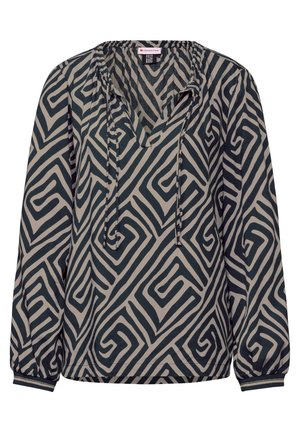 Blouse à manches longues en tissu léger, avec un motif géométrique noir et beige, décolleté en V et poignets élastiques avec finition contrastante.
