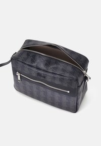 Borsa messenger nera con motivo, chiusura con zip, dotata di un esterno testurizzato e una tasca frontale con dettagli in argento.