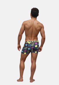 Boxer da uomo con un motivo geometrico nero, giallo e multicolore, dotati di una cintura gialla contrassegnata con "MR UKKR."