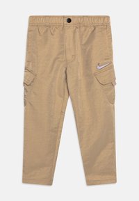 Beige cargo kalhoty vyrobené z lehkého materiálu, s elastickým pasem, bočními kapsami a diskrétním logem Nike.