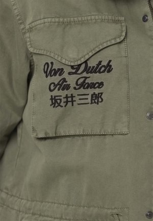 Poche de veste vert olive avec rabat, brodée de "Von Dutch Air Force" et de caractères japonais en fil noir.