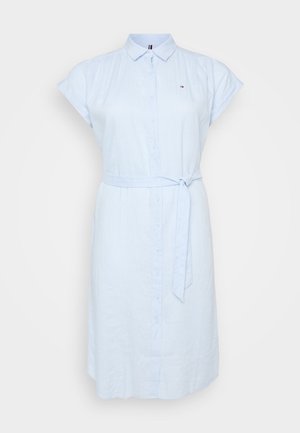 Vestido azul claro de botones, hecho de tejido transpirable. Cuenta con mangas cortas enrolladas, un cinturón atado en la cintura y un detalle de logo sutil.