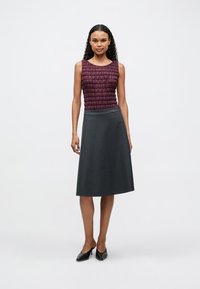 Μπλουζάκι χωρίς μανίκια σε μπορντό χρώμα με υφή, συνδυασμένο με γκρίζα φούστα μέχρι το γόνατο. Απλός σχεδιασμός με φαρδύ σχήμα. Μαύρες γόβες.