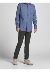 Blå chambray skjorta med knappar och långa ärmar, samt bröstficka, parat med mörkgrå slim-fit byxor och beige mocka ankelstövlar.