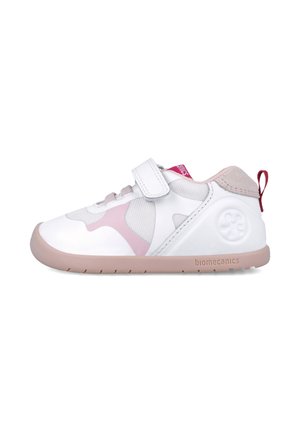 Zapato blanco con acentos rosas, paneles de malla y una correa de velcro. Presenta una punta redondeada y una suela de goma ligera con un agarre texturizado.
