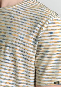 Chemise à manches courtes en coton doux, présentant des rayures horizontales dans des teintes de bleu et d'orange, avec un col rond et une petite étiquette de marque sur le côté.