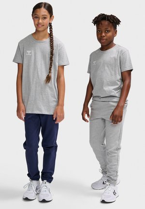 To børn iført tøj: en grå t-shirt med logo og marineblå bukser til venstre; en grå t-shirt og matchende grå joggers til højre.